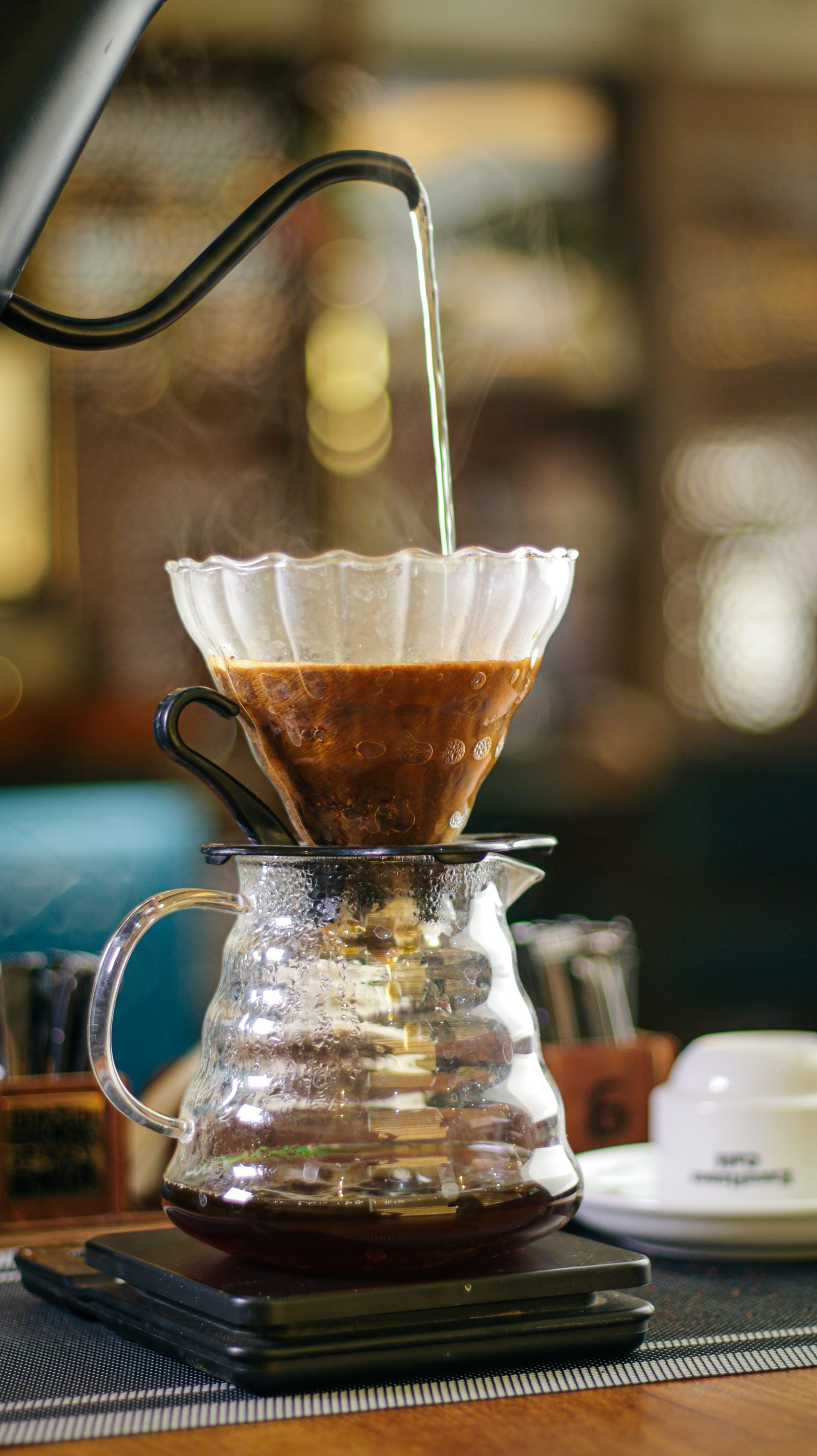 A pour-over coffee being brewed on a scale at Excellence Café's coffee counter.